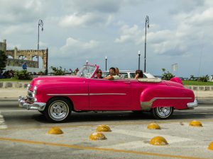 travelers in pink old-timer on street Havana